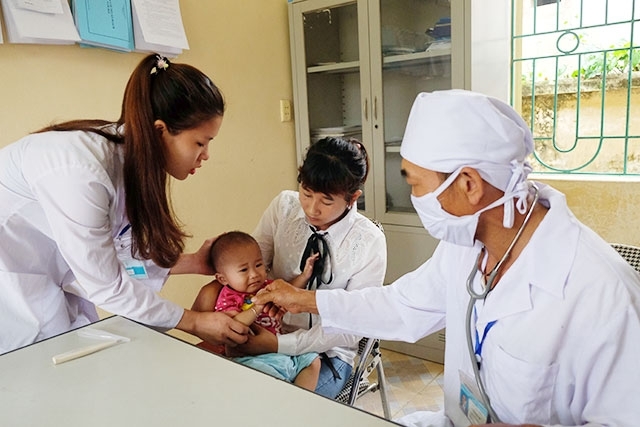 Thầy thuốc Trạm y tế xã Đồng Sơn, huyện Hoành Bồ (Quảng Ninh) khám sức khỏe cho trẻ em.