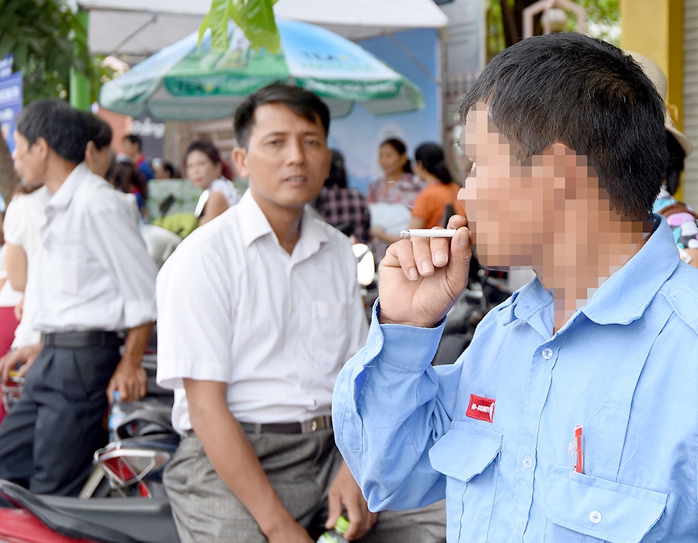 Hút thuốc lá là nguyên nhân chủ yếu gây ra các tổn thương mạn tính trong phổi (Trong ảnh: Người đàn ông vô tư hút thuốc chỗ đông người, chụp trước cổng trường Đại học Xây dựng, Hà Nội). Ảnh: Khánh Linh