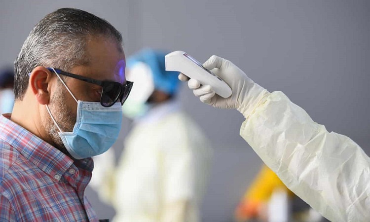 Nhân viên y tế kiểm tra thân nhiệt một người đàn ông ở thành phố Kuwait ngày 12/3. Ảnh: Guardian.
