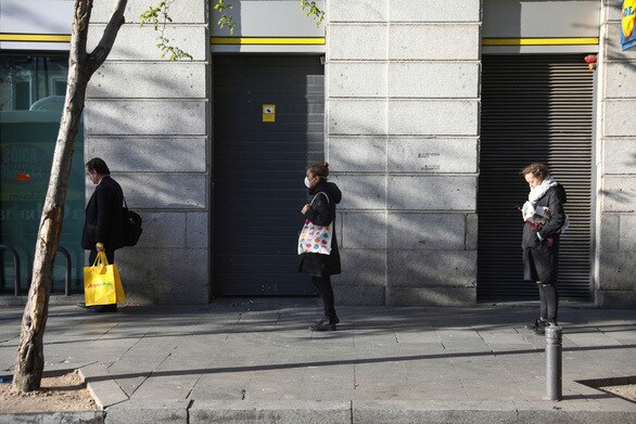 Do dịch bệnh Covid-19, người dân Tây Ban Nha xếp hàng cách xa nhau bên ngoài một cửa hàng ở Madrid theo yêu cầu của chính quyền. Ảnh: Reuters