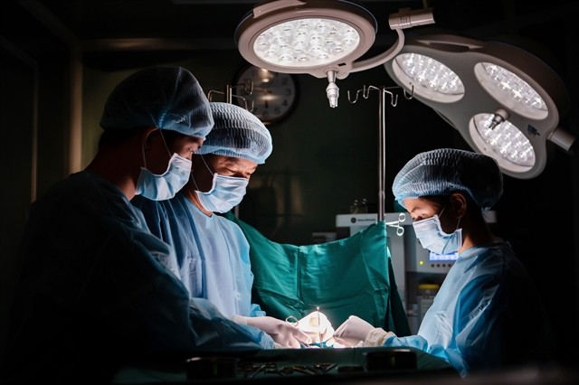 Doctors from JW Korea Plastic Hospital in HCM City perform surgery to remove necrotic tissue from apatient’schest.