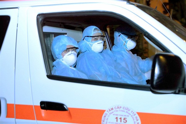 Medical workers from the Hanoi 115 Medical Emergency Centre pick up a COVID-19 patient on Truc Bach Street on March 6.