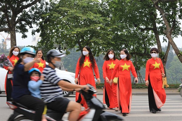 People wear masks while celebrating National Reunification Day (April 30) in Hanoi's Hoan Kiem District, a week after the Government relaxed strict social distancing orders.