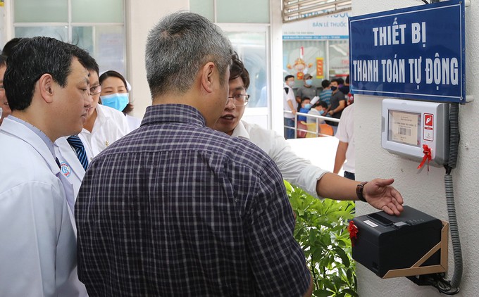 Nhân viên Bệnh viện Chợ Rẫy giới thiệu thiết bị thanh toán tự động với Thứ trưởng Y tế Nguyễn Trường Sơn (áo kẻ) chiều 18/5. Ảnh: N.H