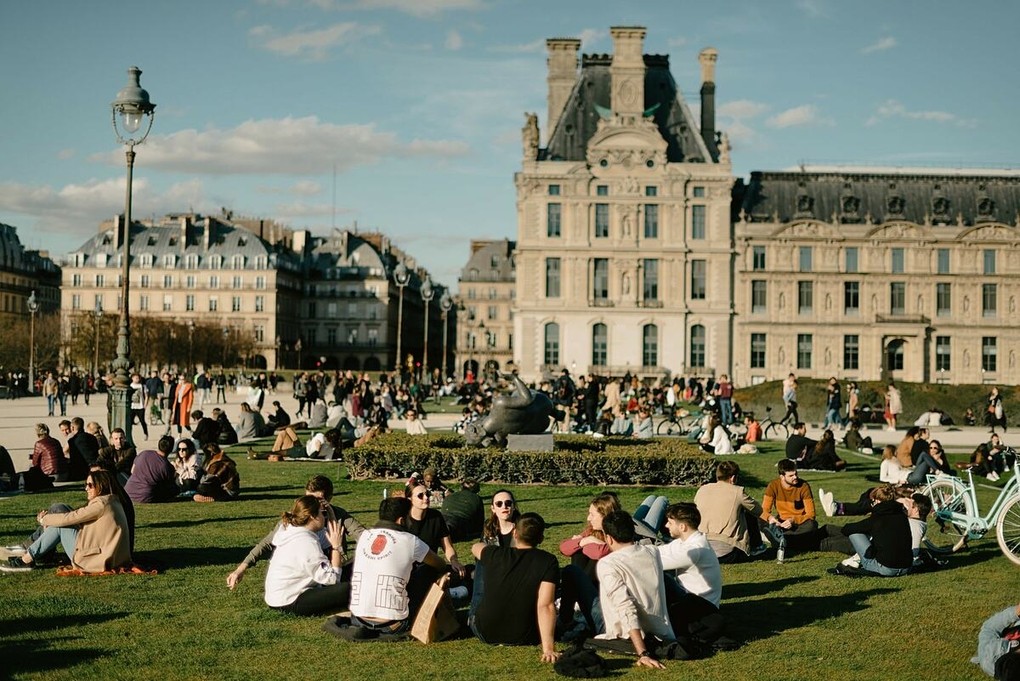 Người dân Paris thư giãn bên ngoài Bảo tàng Louvre, giữa tháng 3. Ảnh: NY Times