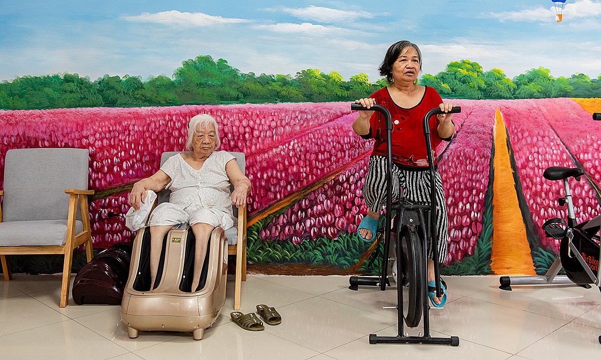 Nguyet (R) works out on a stationary bicycle. Photo by VnExpress/Thanh Hue.