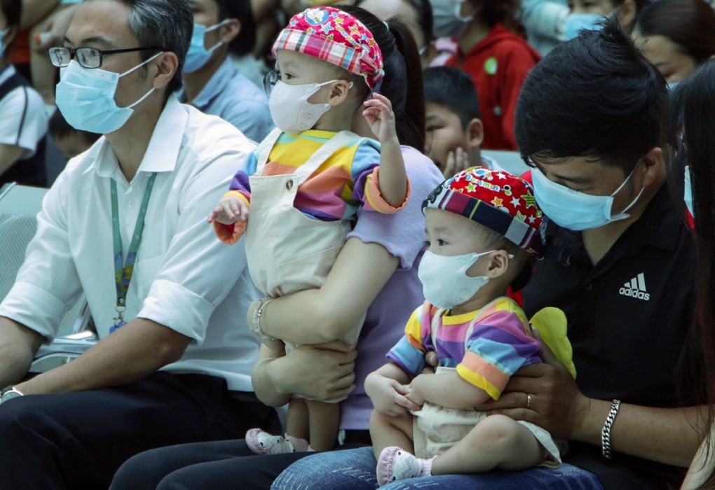 Trúc Nhi (bên trái) đứng vững vàng trong lòng mẹ, vừa nghe hát vừa múa phụ họa, còn Diệu Nhi trầm tĩnh hơn. Ảnh: Thư Anh.