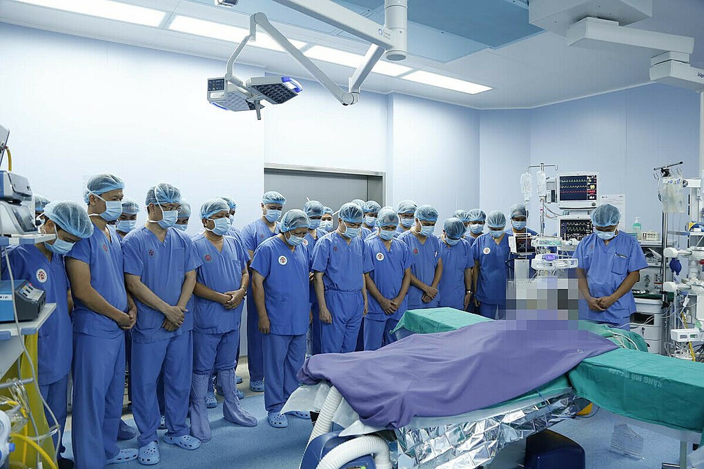 Các bác sĩ cúi đầu mặc niệm người hiến tạng chết não, trước khi phẫu thuật nhận và ghép tạng, hồi tháng 9. Ảnh: Bệnh viện cung cấp.