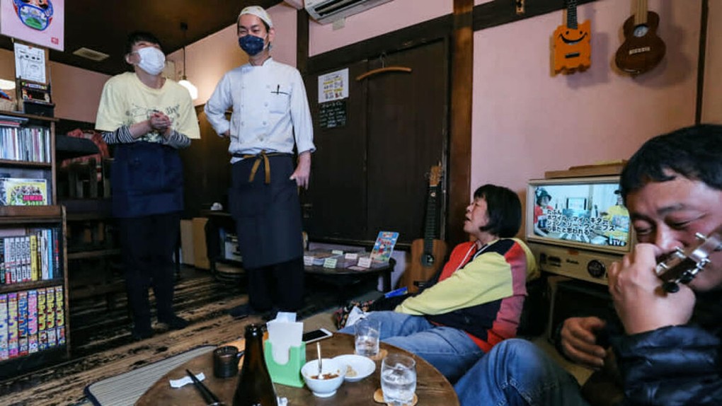 Hiroaki Murata (thứ hai từ trái sang) và vợ nói chuyện với khách hàng và nhạc công trong quán rượu nhỏ ở Tokyo, ngày 13/11. Ảnh: Nikkei