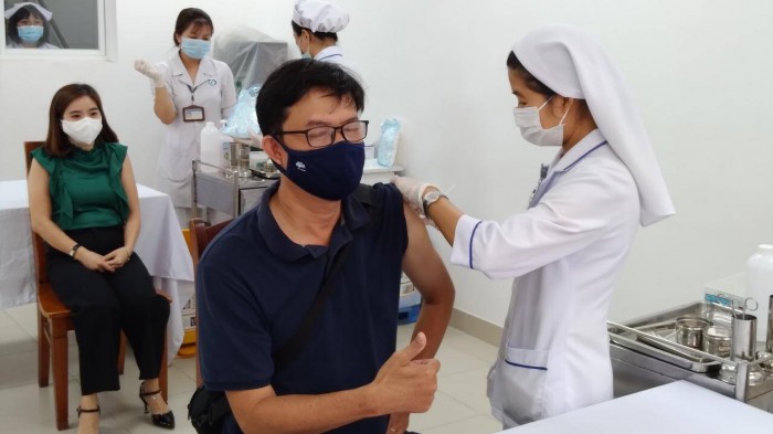 Nhân viên y tế tiêm vaccine phòng Covid-19 cho một phóng viên