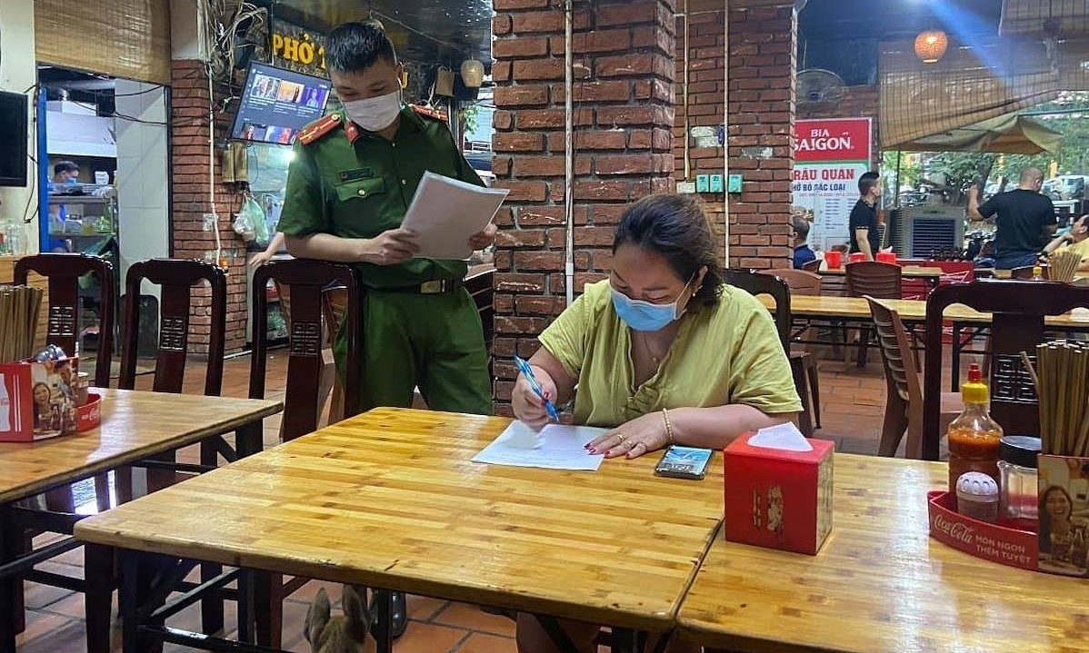 A beer shop owner signs a paper on suspending her business to help prevent Covid spread, May 11, 2021. Photo by VnExpress/Le Khanh.