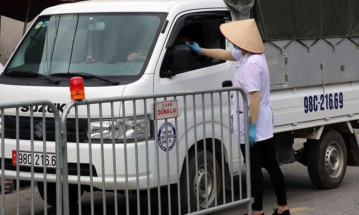 A medic checks the body temperature of a driver at a Covid-19 checkpoint near the Hanoi-Bac Giang border in Hanoi's Soc Son District, May 2021. Photo by VnExpress/Vo Hai.