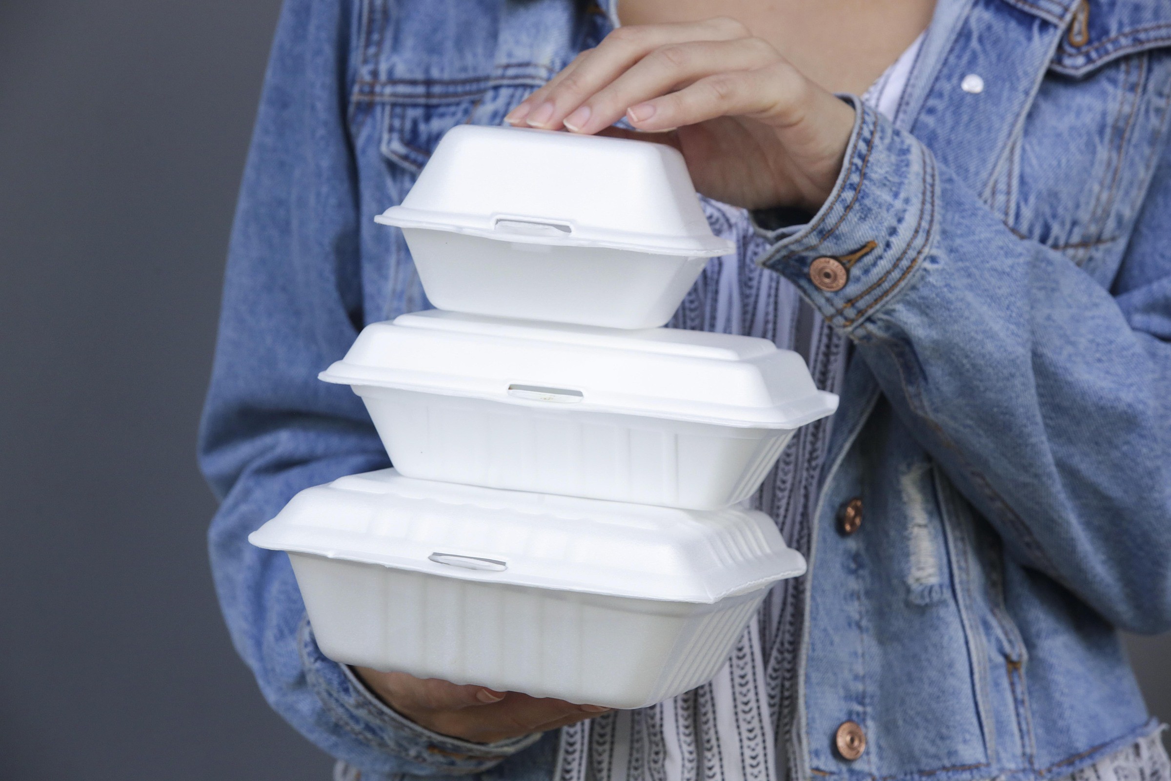 A woman holds takeaway styrofoam boxes. Photo by Shutterstock/triocean.