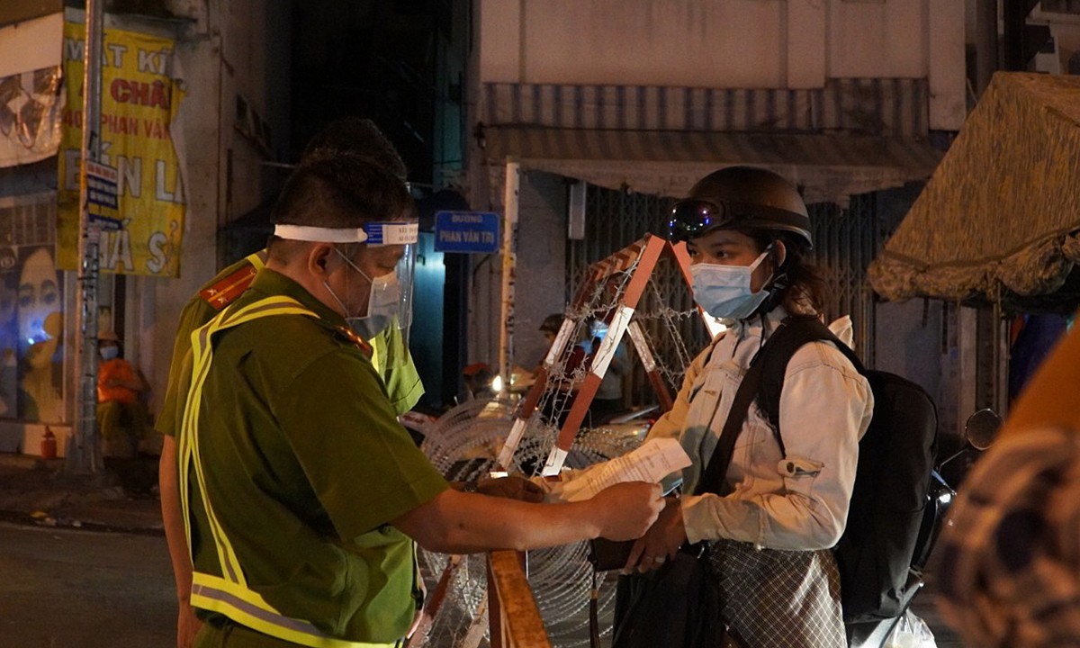 Police check papers of a woman who wants to get through a Covid-19 checkpoint in Go Vap District, now the biggest Covid hotspot in HCMC, May 31, 2021. Photo by VnExpress/Gia Minh.