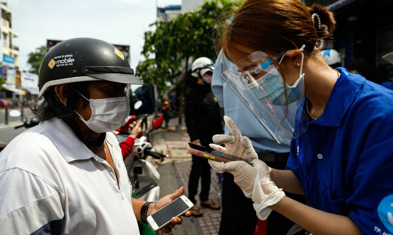 A volunteer (R) checks the QR code for the health declaration of a man who wants to get through a Covid-19 checkpoint in HCMC's Go Vap District, June 6, 2021. Photo by VnExpress/Huu Khoa.