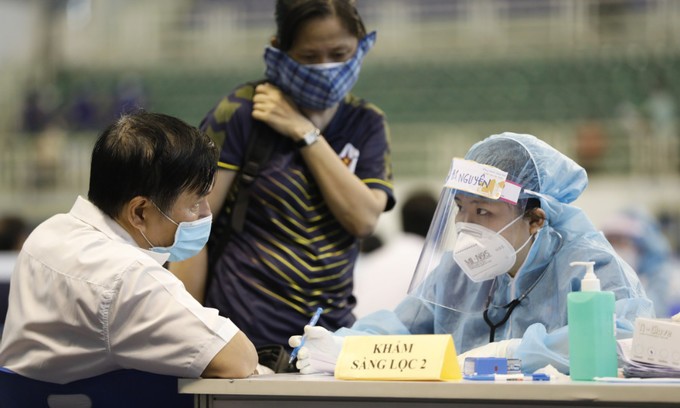 A medical staff checks a man's health before vaccination in Ho Chi Minh City in June 2021. Photo by VnExpress/Huu Khoa.