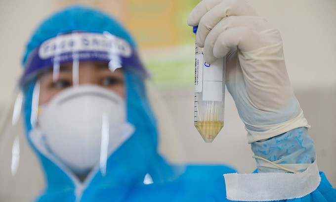 A medical worker holds up a vial containing samples for Covid-19 testing in HCMC's District 1, July 3, 2021. Photo by VnExpress/Huu Khoa.