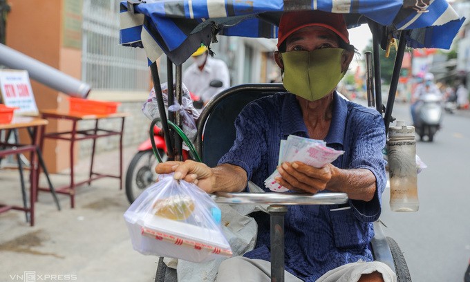 A lottery ticket vendor receives a charity meal from benefactors in HCMC, June 2021. Photo by VnExpress/Quynh Tran.