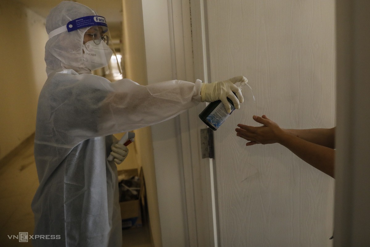 Doctor Nguyen Tran Anh Thu sprays disinfectant on a Covid-19 patient’s hands.
