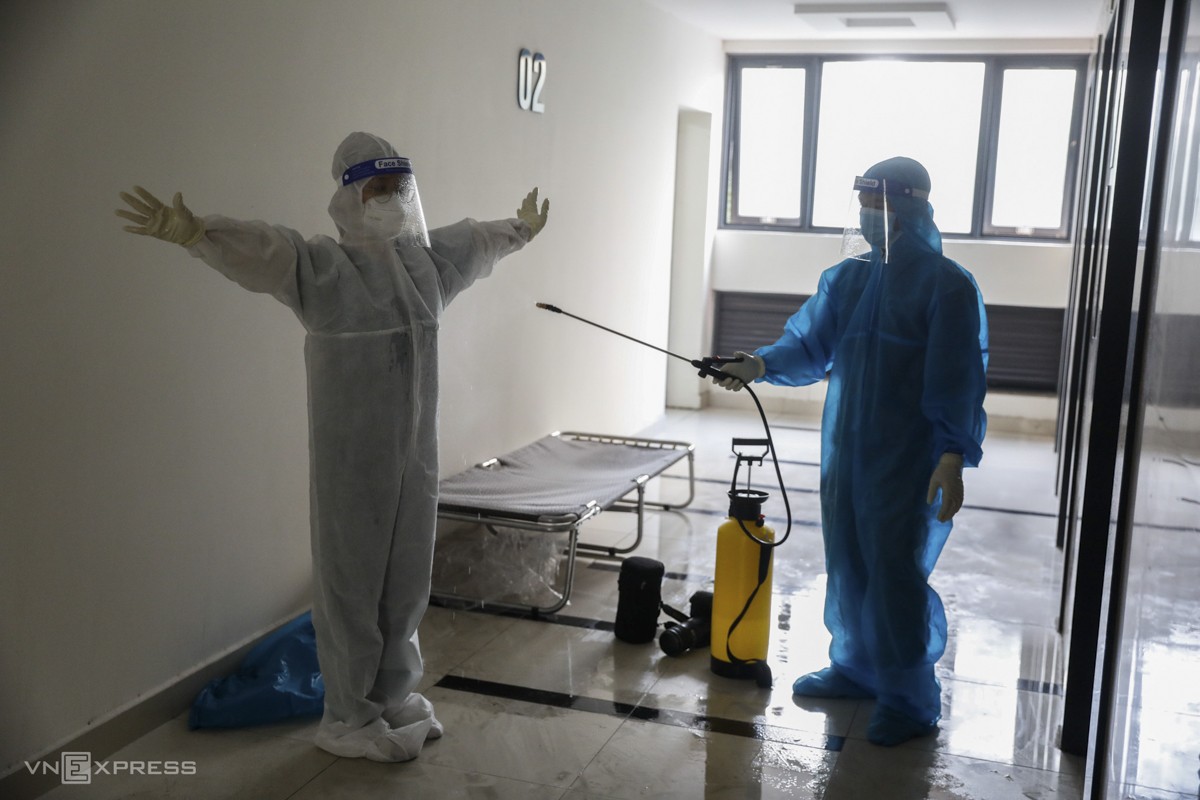 A staff member disinfects Thu after she completes the task of checking patients.