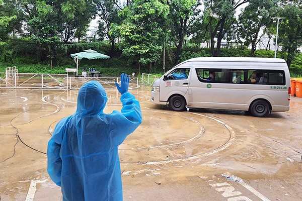 Nhân viên y tế vẫy tay chào khi các F0 khỏi bệnh lên xe về nhà.