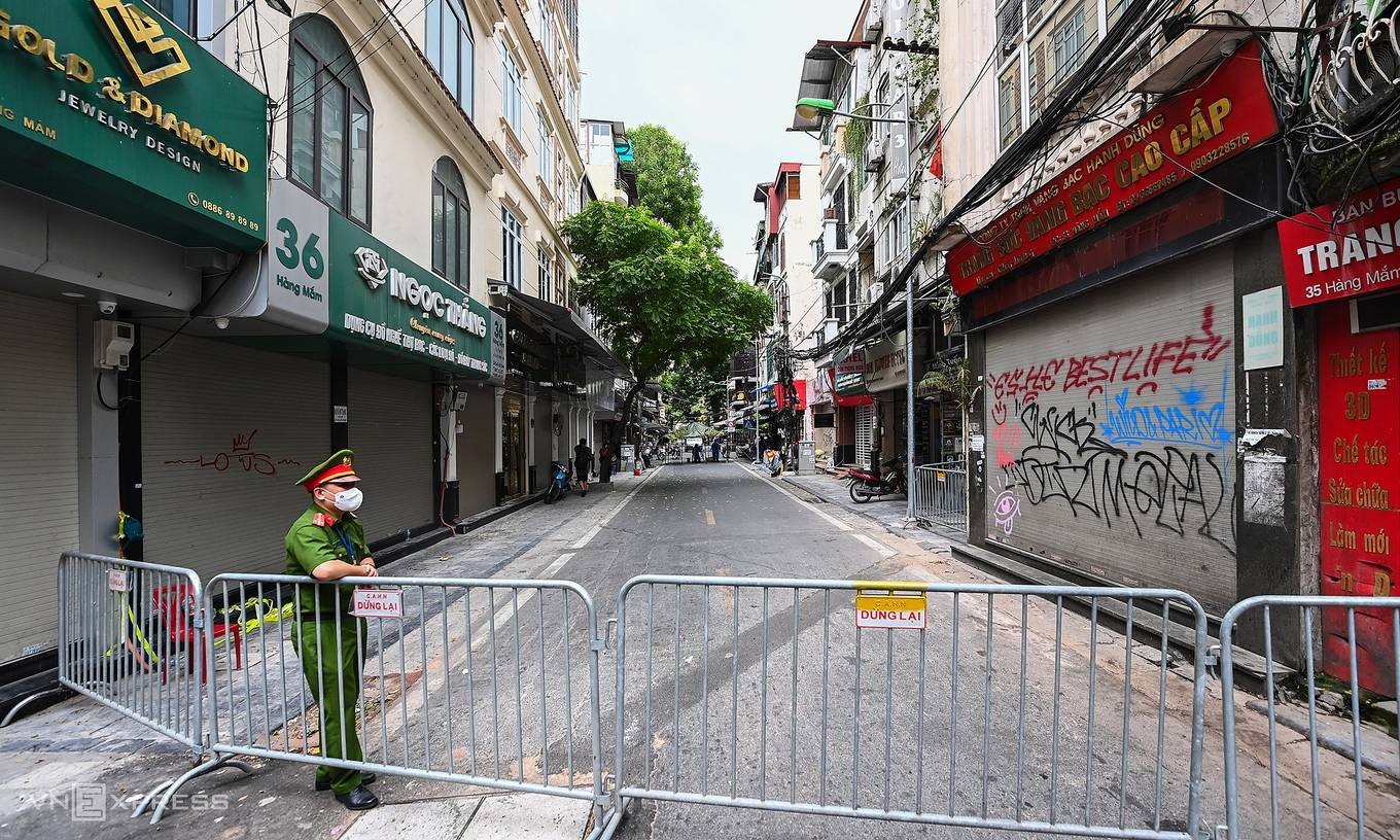 A police officerr stands guard at a barrier to isolate an infected area in downtown Hanoi, July 2021. Photo by VnExpress/Giang Huy.