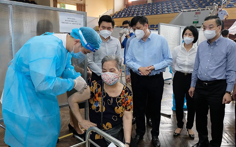 Bộ trưởng Nguyễn Thanh Long kiểm tra điểm tiêm ở nhà thi đấu Trịnh Hoài Đức, thăm hỏi những người tới tiêm. (Ảnh: Bộ Y tế)