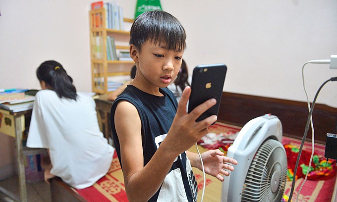 A boy uses his smartphone at his home in Hanoi, September 2021. Photo by VnExpress/Pham Chieu