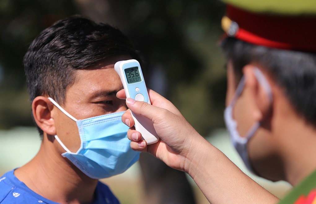 Cơ quan chức năng đo thân nhiệt người từ Đà Nẵng về Quảng Nam tại chốt kiểm dịch đường 603B, phường Điện Ngọc, thị xã Điện Bàn sáng 29/7. Ảnh: Đắc Thành.