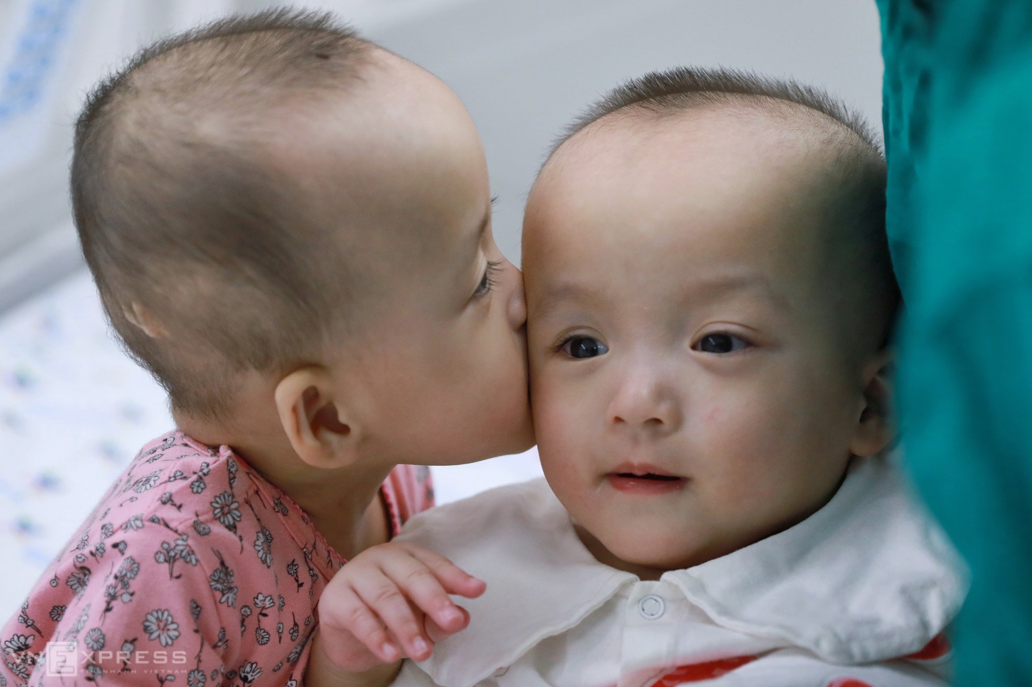 Vừa được bế sang giường bên cạnh chơi, Diệu Nhi liền ôm hôn và nắm tay Trúc Nhi.