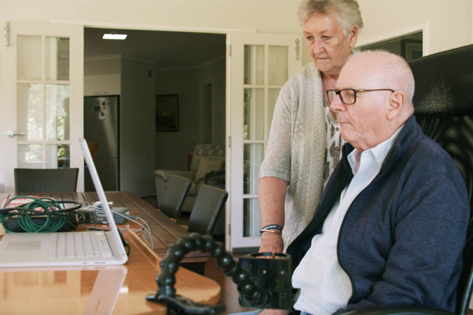 Graham Felstead, bệnh nhân đầu tiên được cấy thiết bị Stentrode, đang sử dụng để vận hành máy tính trong khi Nancy, vợ ông đứng bên cạnh theo dõi. Ảnh: WSJ