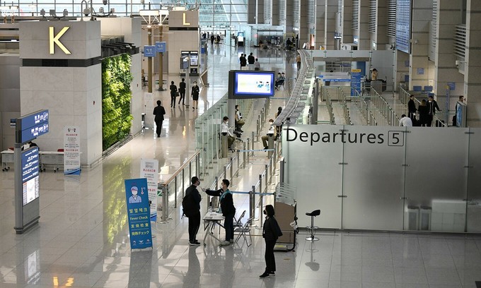 A member of the South Korean military support team checks the body temperature of a passenger at Incheon international airport, west of Seoul, March 17, 2020. Photo by AFP/Jung Yeon-je.