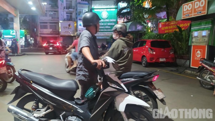 Người dân dắt xe máy rời cây xăng Saigon Petro. Phía trước cây xăng, nhiều ô tô cũng phải quay đầu.