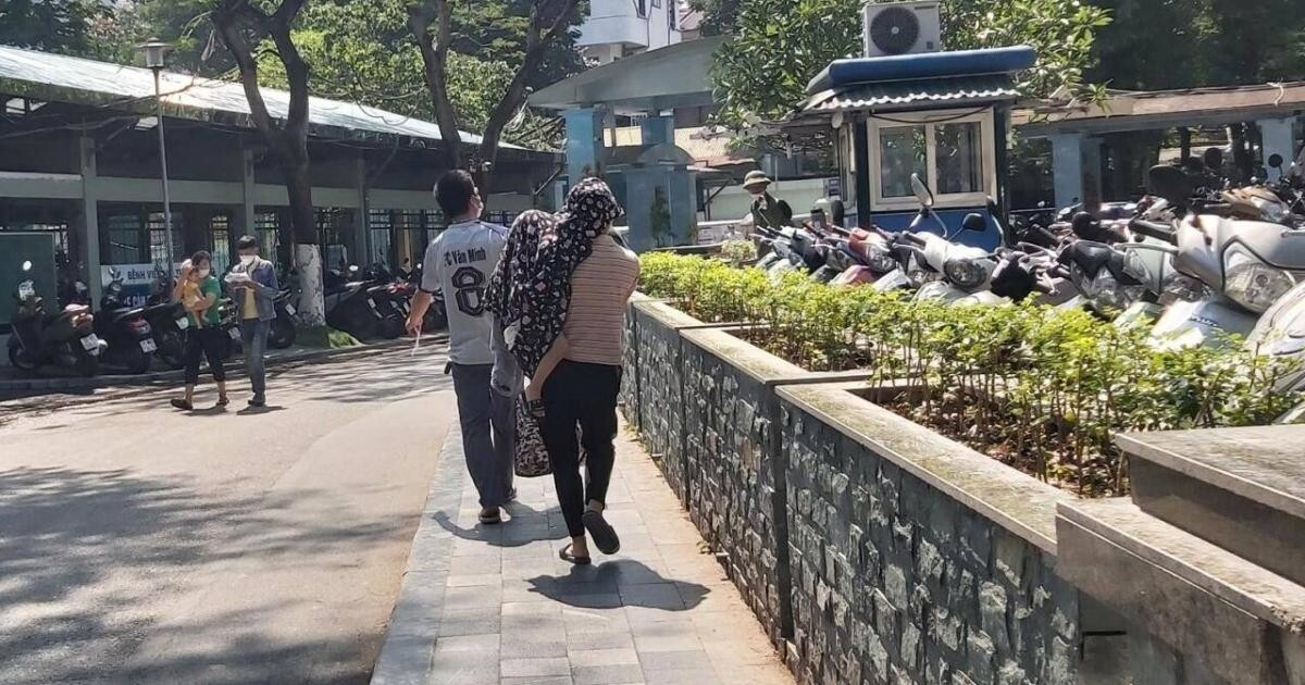 Bế con trên tay, người phụ nữ đội áo trùm đầu rảo bước thật nhanh tránh ánh nắng gay gắt