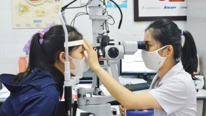 Bác sĩ khám cho 1 bệnh nhân viêm kết mạc cấp.